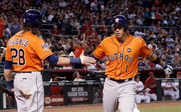 Houston Astros players celebrating a run during a baseball game in orange uniforms