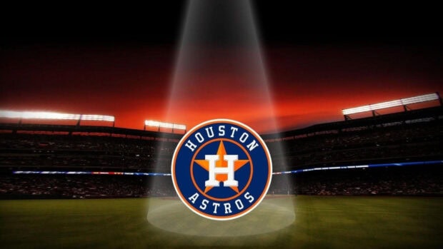 The Houston Astros logo illuminated by a spotlight in a stadium at sunset