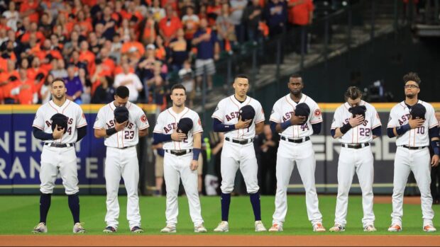 Houston Astros players standing solemnly during the national anthem on the field