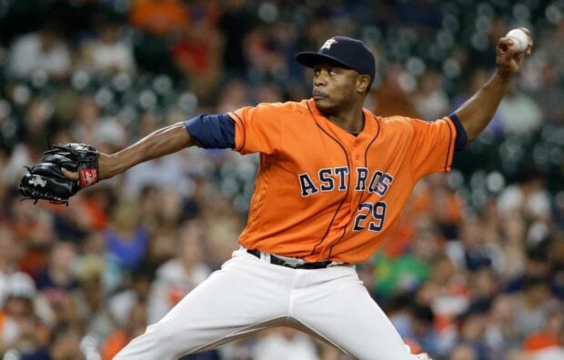 Houston Astros player pitching the ball during a game in an orange uniform number 29