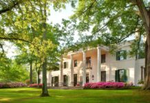 Historic Houston mansion surrounded by lush greenery and blooming flowers in Texas