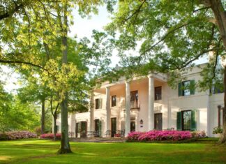 Historic Houston mansion surrounded by lush greenery and blooming flowers in Texas