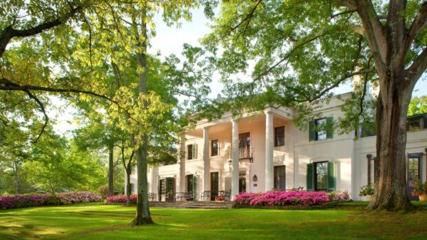 Historic Houston mansion surrounded by lush greenery and blooming flowers in Texas