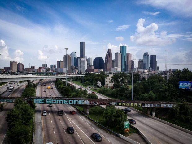 A vibrant cityscape of Houston featuring its skyline and highways under a blue sky