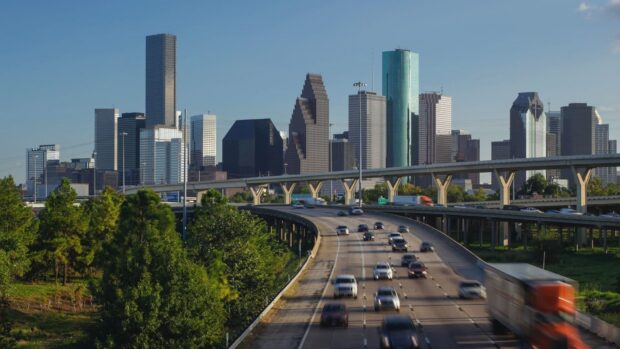 Houston Texas skyline with busy highway and green trees in clear daylight