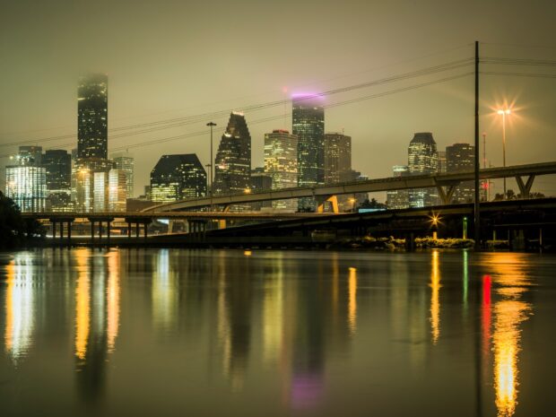 Night view of Houston Texas city skyline with illuminated buildings reflecting on the water