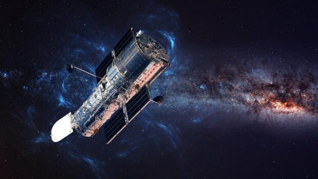 Hubble telescope exploring deep space with galaxy and stars in the background