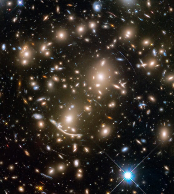 A cluster of galaxies captured by Hubble showing distant stars and cosmic structures