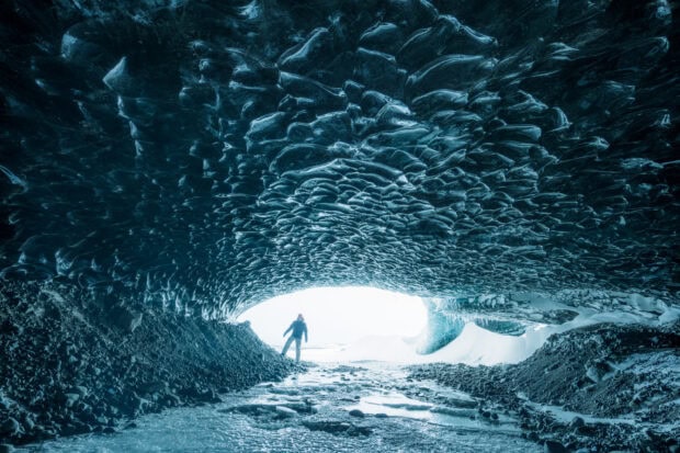 A person exploring the stunning ice cave formations inside a glacier tunnel