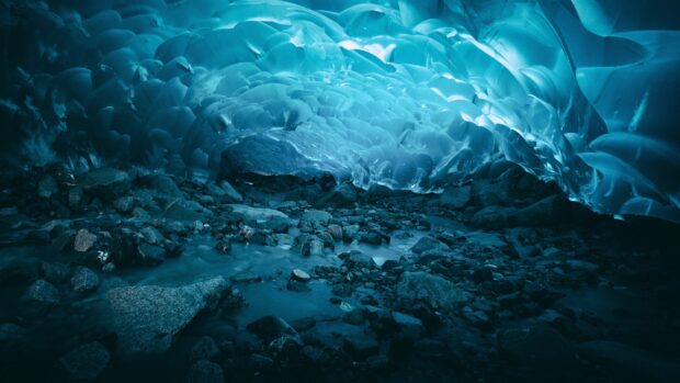 A mesmerizing ice cave with intricate blue formations and rocky ground inside the cave