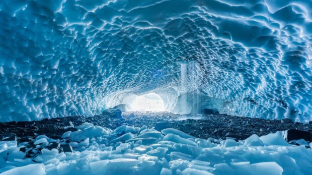 Inside an ice cave with textured icy walls and scattered ice chunks on the ground