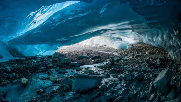 Stunning natural ice cave with rocky ground and glowing blue ice walls