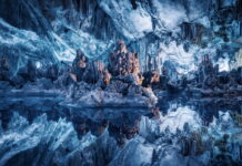 Stunning ice cave formations reflected in crystal clear water inside the cave