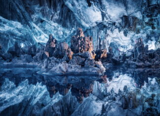 Stunning ice cave formations reflected in crystal clear water inside the cave