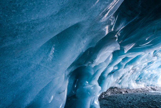 Stunning ice cave formation showcasing blue ice textures and rocky ground inside the cave