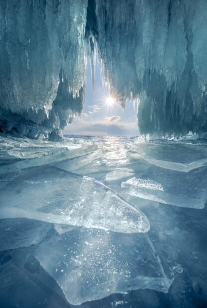 Sunlight shining through ice cave with clear ice and frozen landscape inside the cave