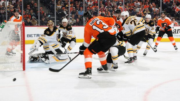 Ice hockey players competing near the goal with a goalie attempting to block the puck