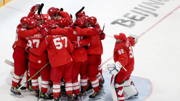 Ice hockey players in red uniforms celebrating on ice rink after a game