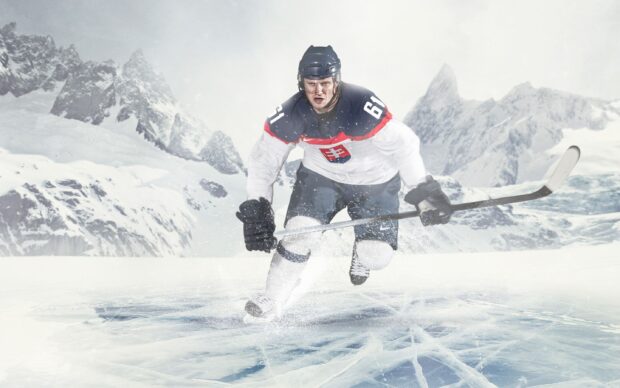 Male ice hockey player skating swiftly on the ice in a snowy mountain setting
