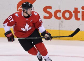 Ice hockey player wearing a red jersey with a maple leaf skating on ice rink