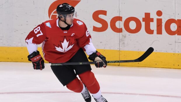 Ice hockey player wearing a red jersey with a maple leaf skating on ice rink