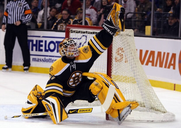 Ice hockey goalie in black and yellow uniform making a save during a game