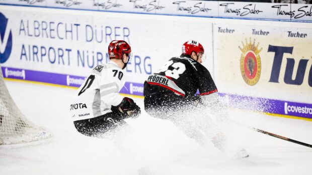 Ice hockey players competing on ice rink with fast skating and ice spray