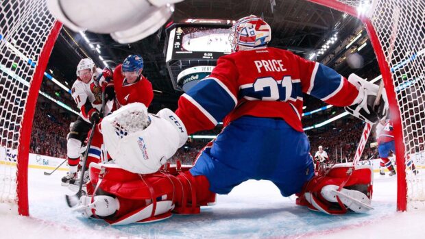 Ice hockey players battling near the goal with the goalie blocking a shot in an ice hockey match