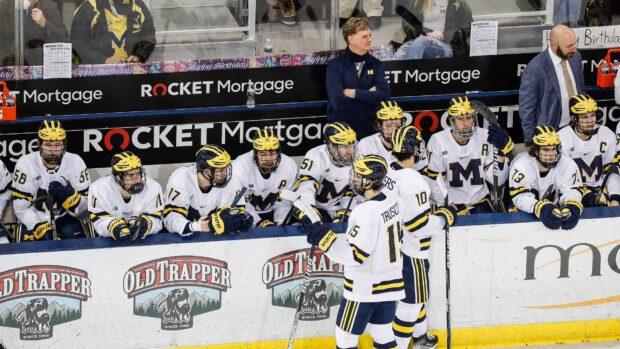 Ice hockey players with yellow helmets in white uniforms gathered on the bench during the game