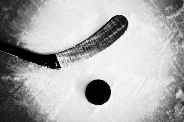 Close up of ice hockey stick and puck on the ice surface