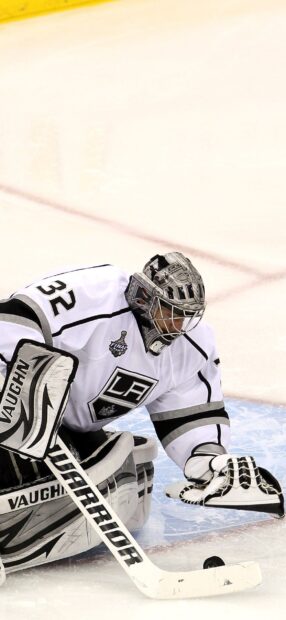Ice hockey goalie in white uniform making a save on the ice rink