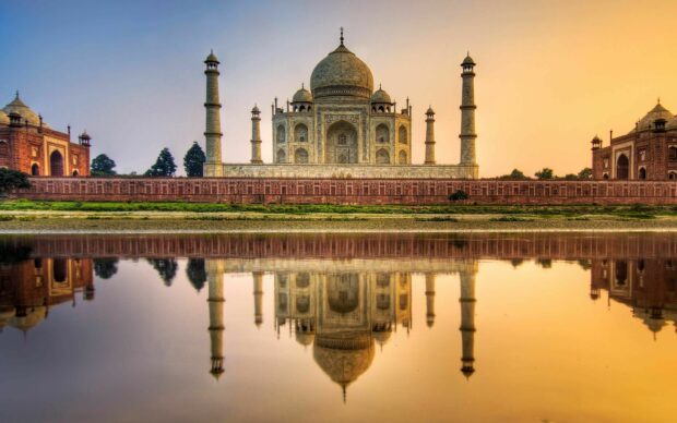 The Taj Mahal reflecting in water at sunset with clear sky in India