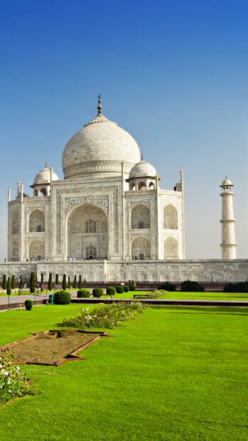 The Taj Mahal is a famous India monument with white marble and green gardens under a clear blue sky