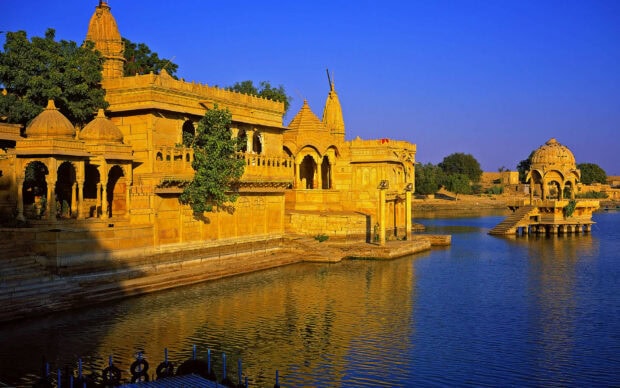 Ancient Indian architecture on the riverbank with clear blue sky and water reflections
