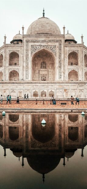 The iconic India monument reflecting in the water with people walking nearby