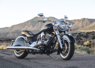 A black Indian bike parked on a road with mountains in the background