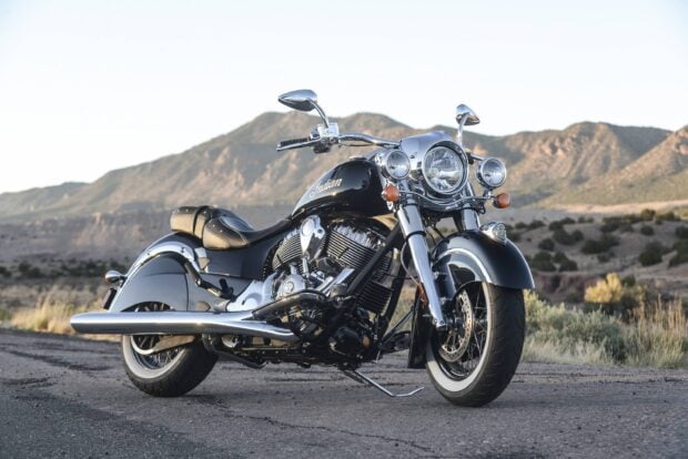 A black Indian bike parked on a road with mountains in the background