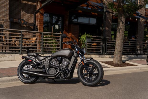A classic Indian bike parked on the street in front of a modern building