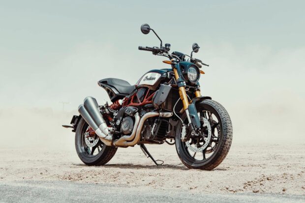 A powerful Indian bike stands on a dusty road with clear sky in the background
