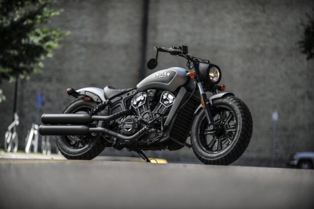 Matte black Indian bike parked on the street with a blurred brick wall background