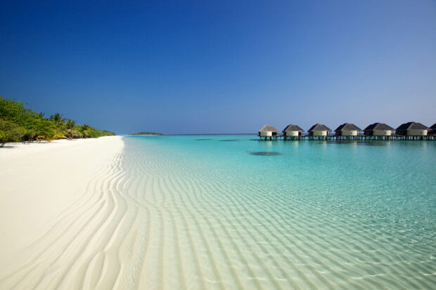 Clear turquoise water along the Indian Ocean coastline with tropical huts and white sandy beach
