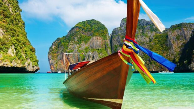 Traditional wooden boat near green rocky cliffs of Indian Ocean