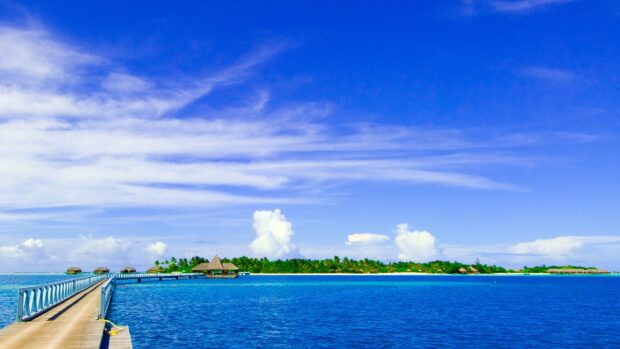 Tropical island view with Indian Ocean and wooden pier under blue sky