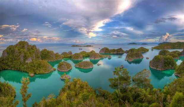 Aerial view of Indonesia islands with lush greenery and turquoise waters under a cloudy sky