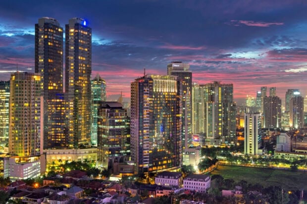 Cityscape of Indonesia with illuminated skyscrapers during sunset in the evening sky