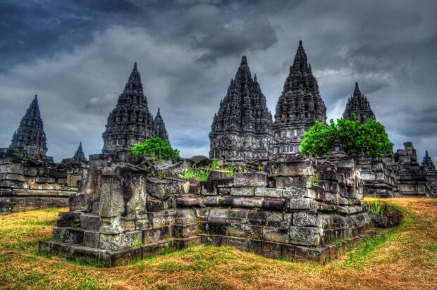 Ancient Indonesia temple ruins surrounded by lush greenery under a cloudy sky
