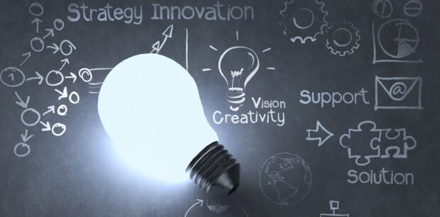 Bright light bulb symbolizing innovation and creativity on a chalkboard with strategy diagrams
