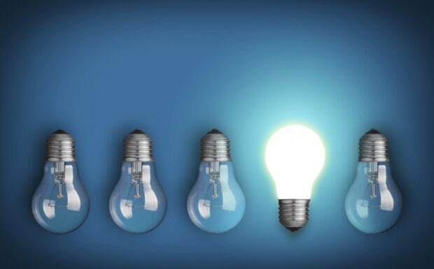 A row of light bulbs with one glowing representing innovation concept