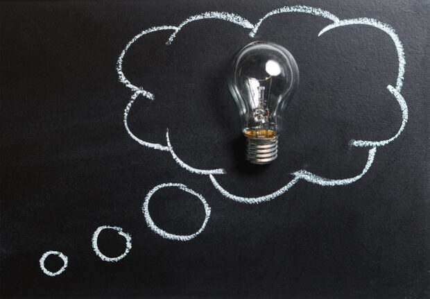 Lightbulb inside a thought bubble drawn on a chalkboard illustrating innovation concept