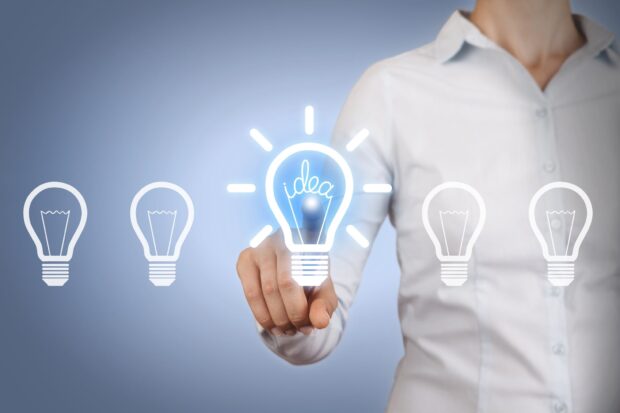 Person pointing at glowing light bulb idea concept representing innovation